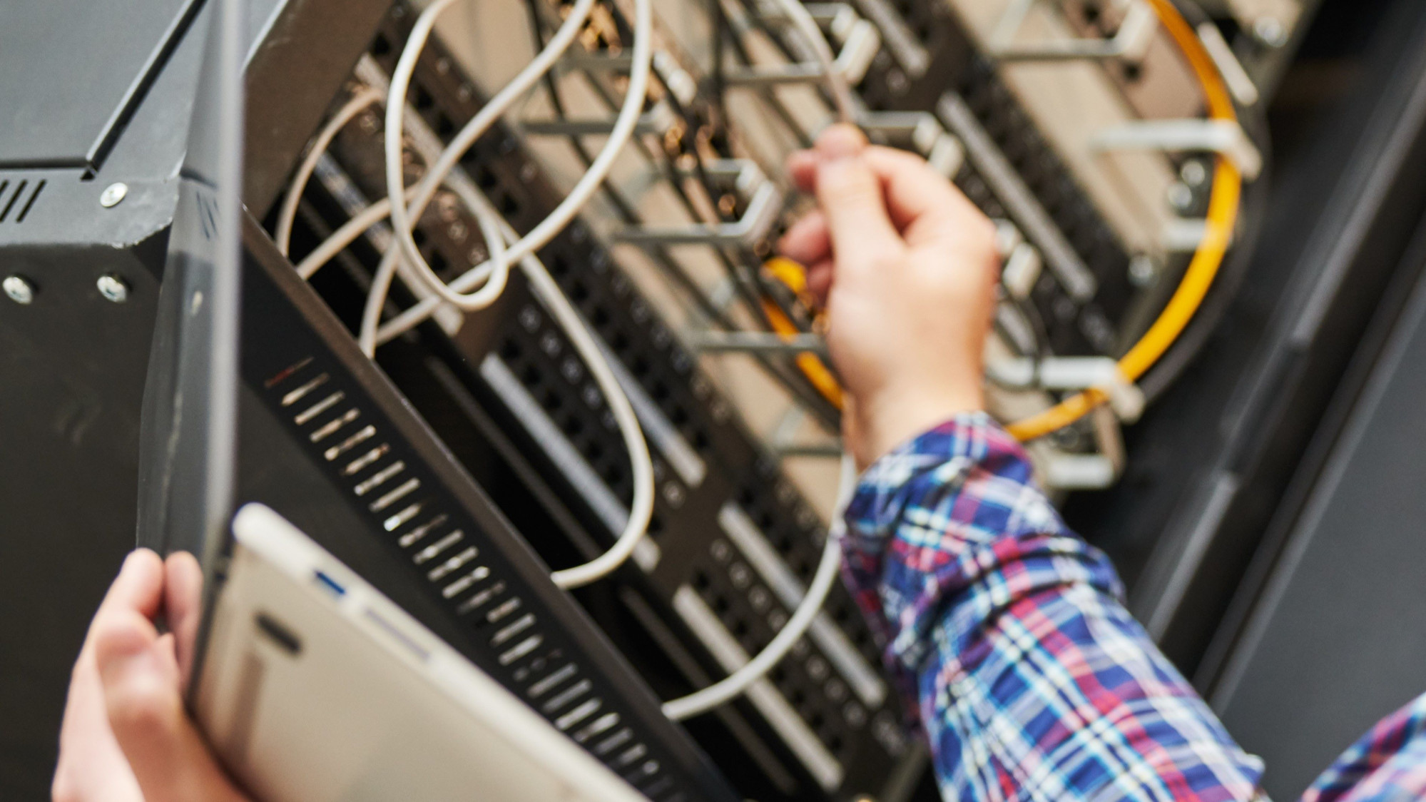 Adobe Stock photo of IT Technician checking and installing cable connections.